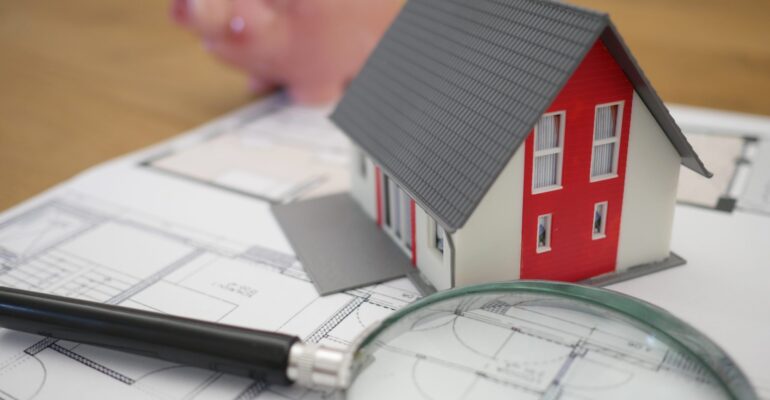 white and red wooden house beside grey framed magnifying glass